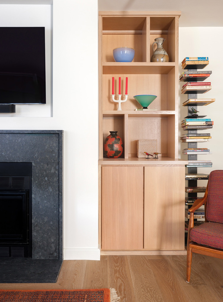 Living room built-in shelves – Modern built-in shelving and black stone fireplace surround in a Central West End home renovation by Hercules Design Build, a trusted design build home remodeling company in St. Louis.