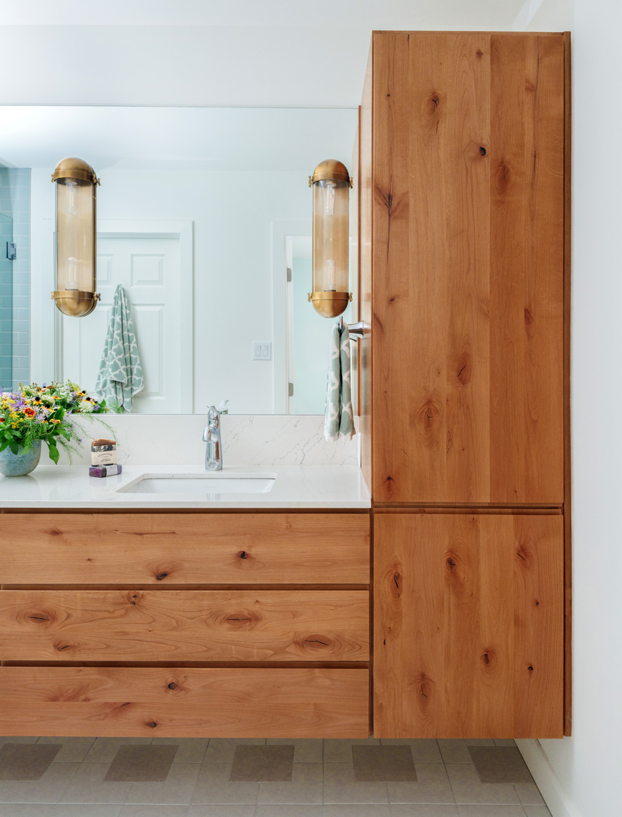 Warm wood vanity in modern bathroom – Custom knotty wood vanity with quartz countertop and brass sconces in a remodeled bathroom. A Hercules Design Build project in the Central West End blending natural warmth with clean modern lines.