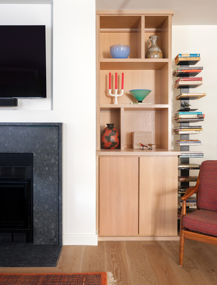 Custom shelving beside modern fireplace – Light oak shelving with curated decor sits beside a black stone fireplace in this architect remodeling St. Louis project. Designed and built by Hercules Design Build, a trusted general contractor in St. Louis.