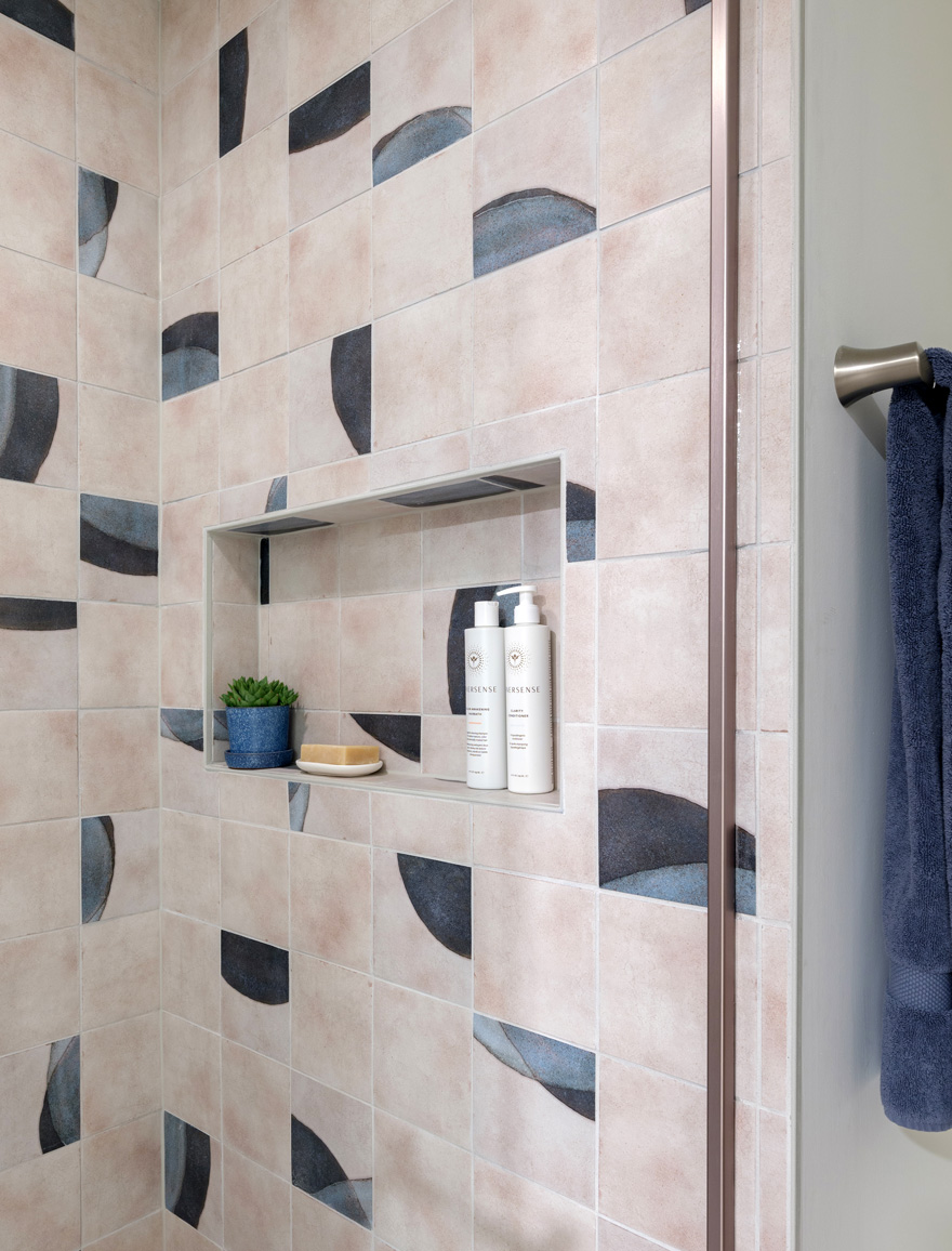A shower with blue and white tile and gold accents
